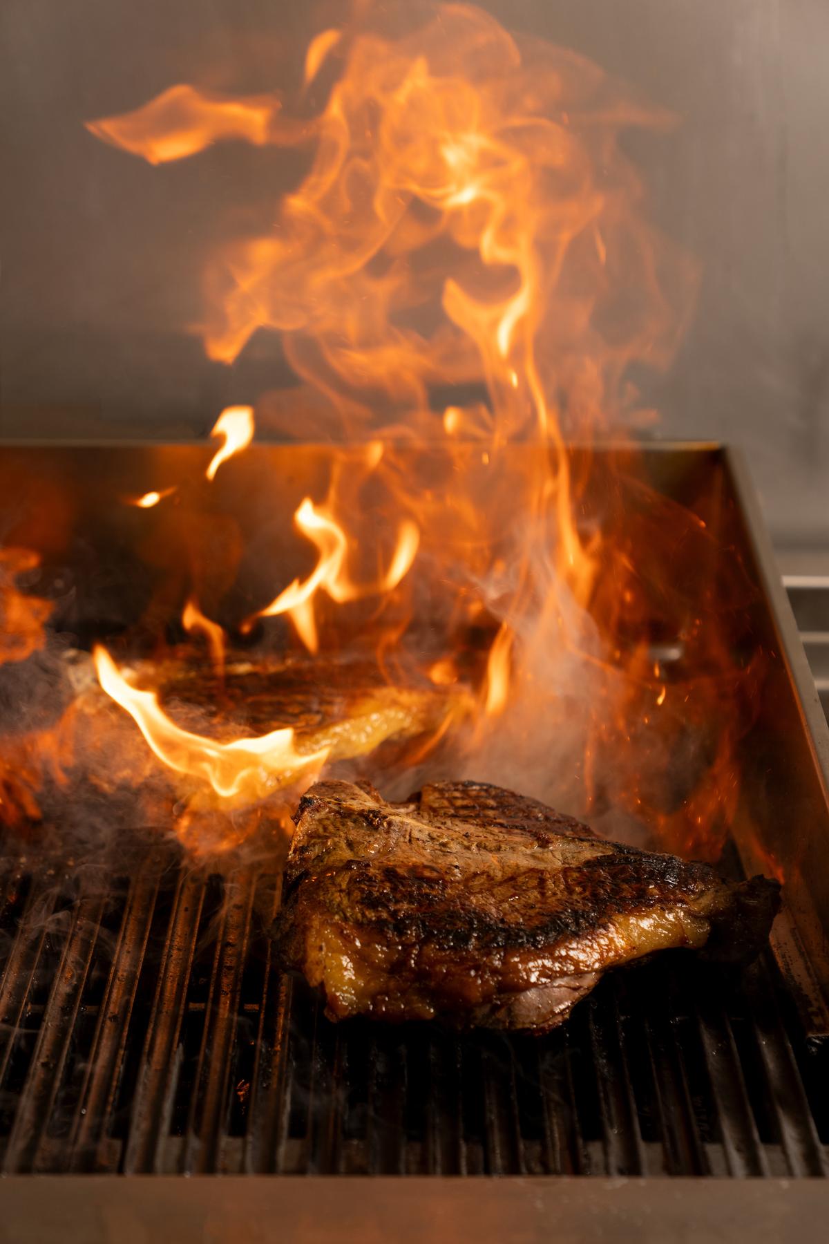 Bistecca alla fiorentina sulla griglia tra le fiamme